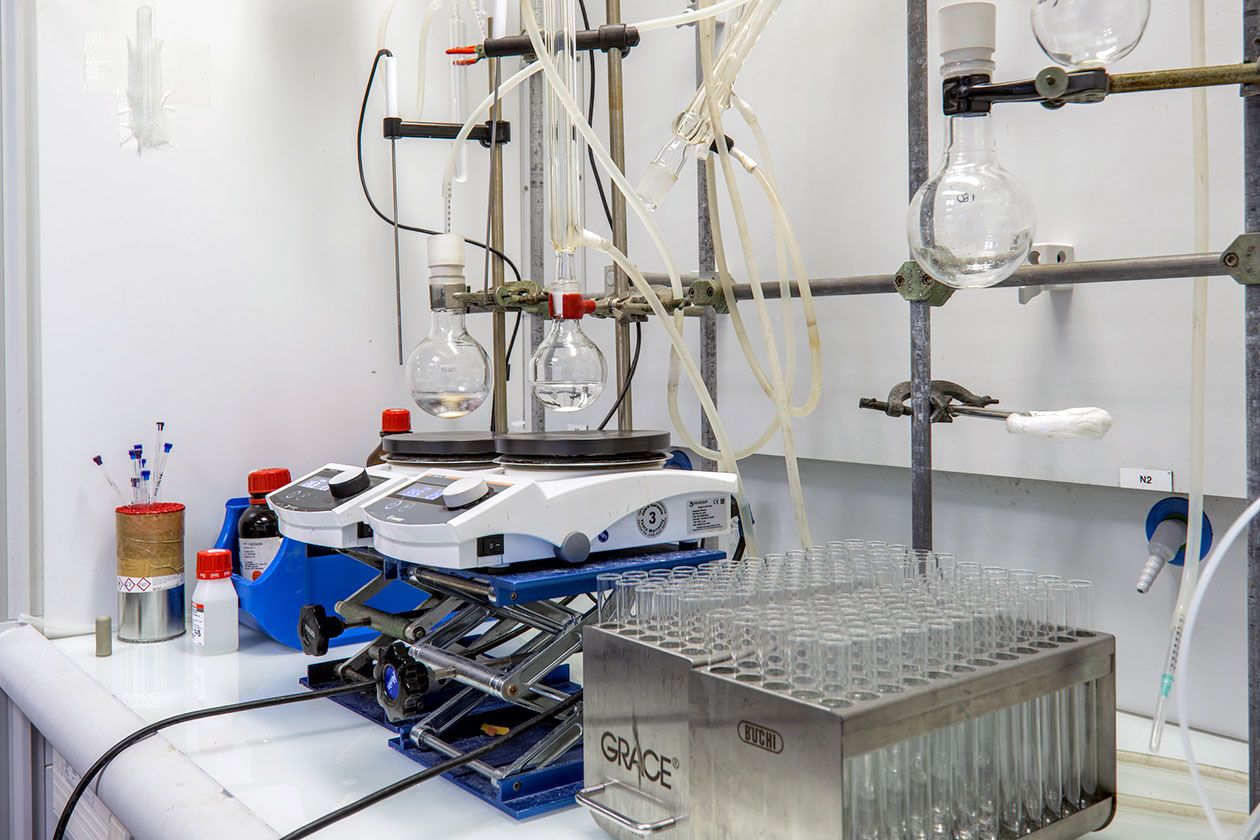 <hr>Hotte aspirante avec deux réactions chimiques en cours et deux racks issus d’une purification sur puriFlash.